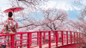 A woman in a kimono walks across a bridge adorned with cherry blossoms, promoting Japan Cherry Blossom Cruises 2026.